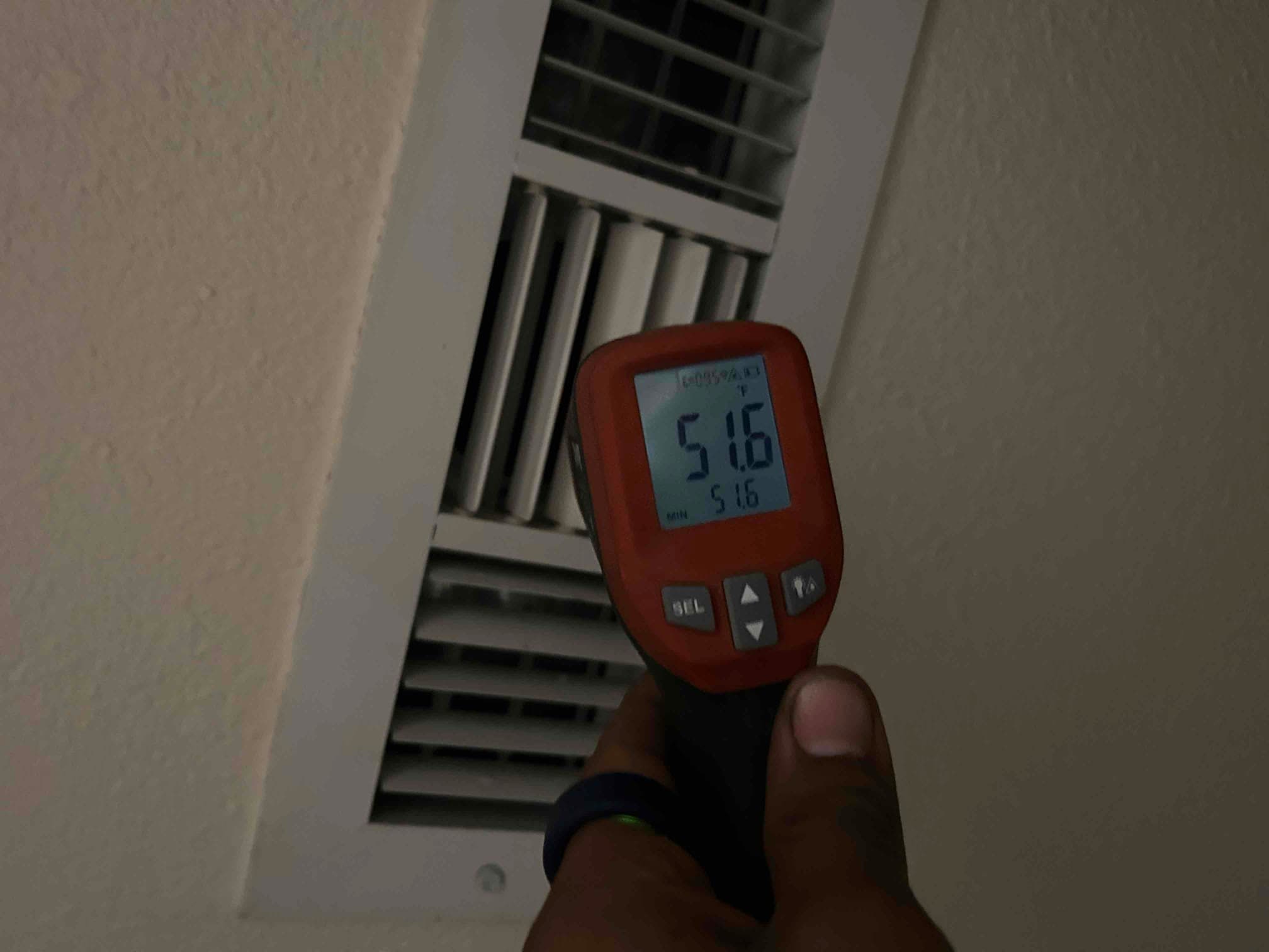 HVAC technician checking supply-air temperature during an AC diagnostic in San Jose